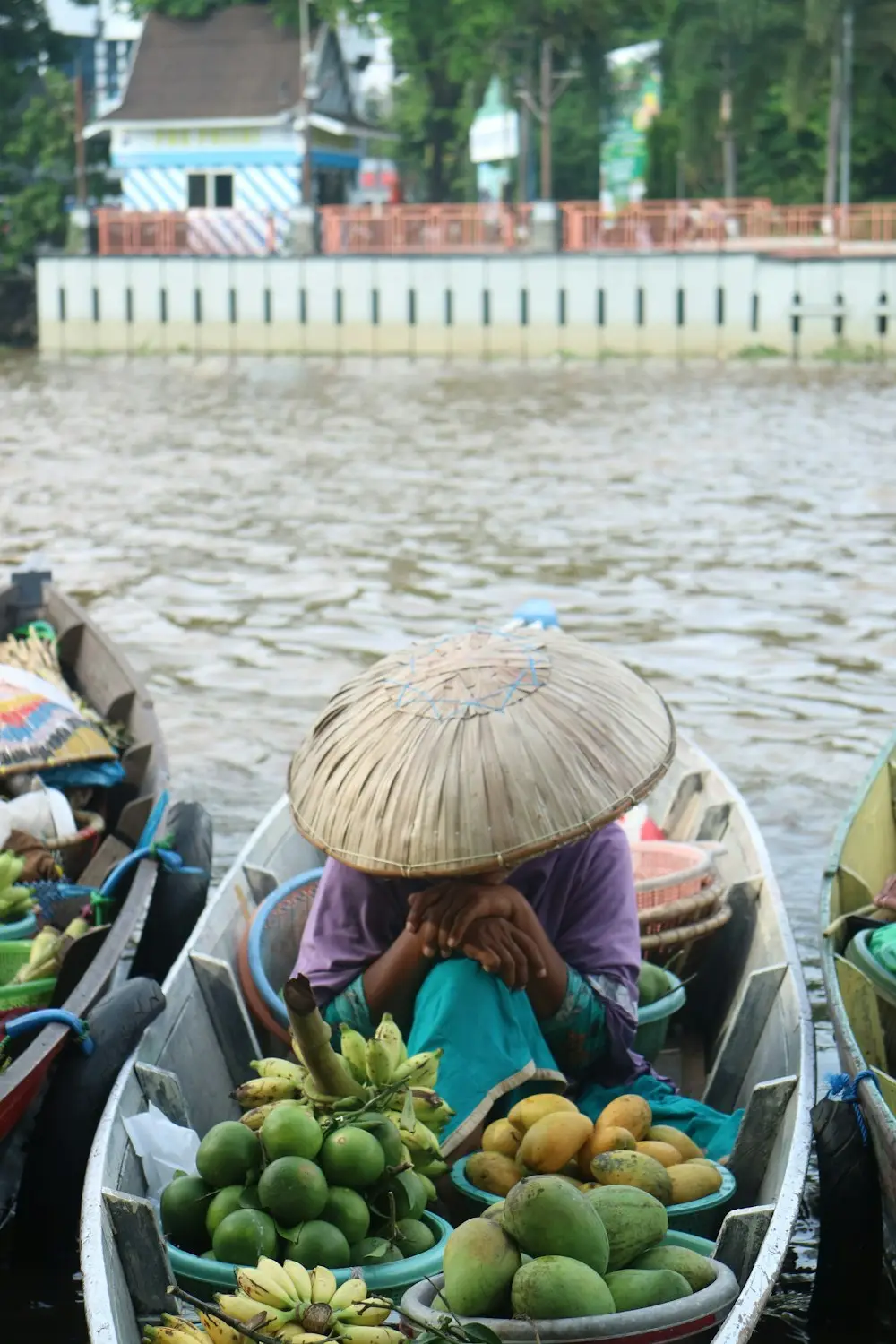 Pedagang bertanggui menjual pisang, jeruk, dan mangga dari jukung