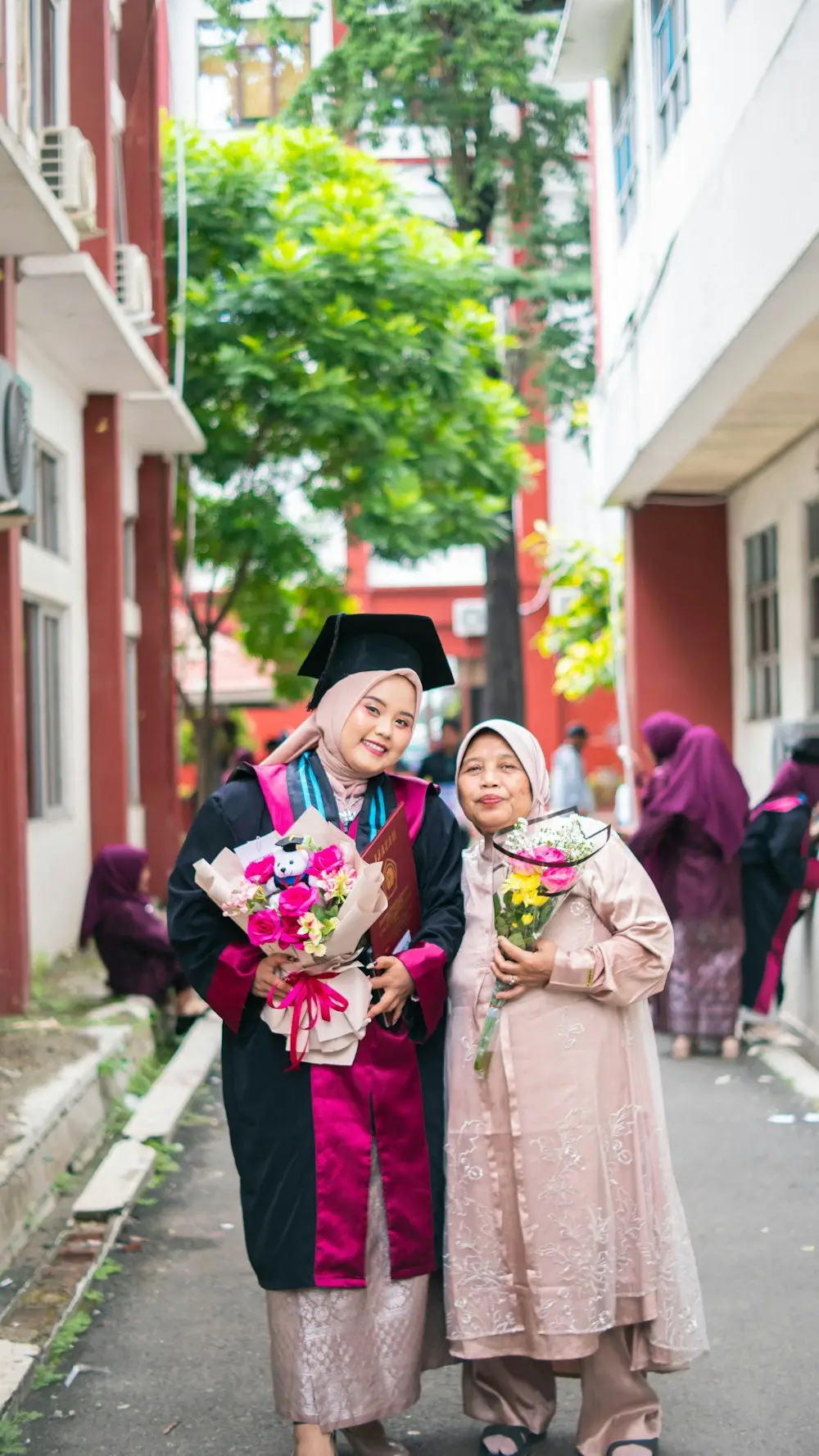 Wisudawati bertoga menggandeng ibunya sambil membawa buket bunga