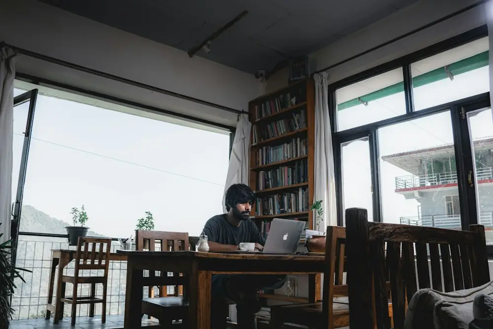 Ruang kafe dengan meja kayu panjang dan jendela besar